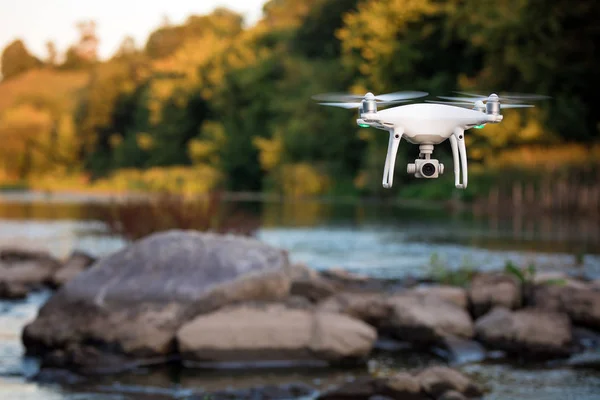 quadcopter drone flying with a camera over a lake.