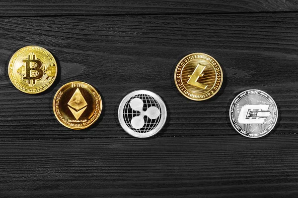 Ahşap zemin üzerinde bitcoin, dalgalanma ve ethereum sembollü gümüş ve altın sikkeler.