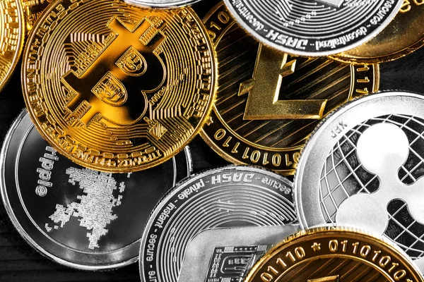 Ahşap zemin üzerinde bitcoin, dalgalanma ve ethereum sembollü gümüş ve altın sikkeler.