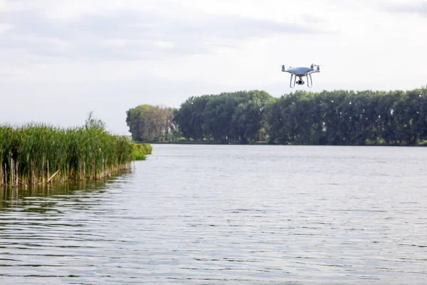 quadcopter drone flying with a camera over a lake.