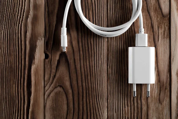Ahşap arka planda kablo telefon şarj cihazları