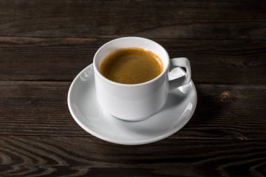 Siyah ahşap zemin üzerine beyaz fincan sade kahve