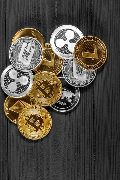 Ahşap zemin üzerinde bitcoin, dalgalanma ve ethereum sembollü gümüş ve altın sikkeler.