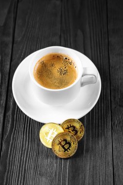 Tahta bir arka planda izole edilmiş kahve fincanının üzerinde duran kripto altın bitcoin.