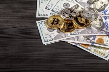 Ahşap zemin üzerinde bitcoin, dalgalanma ve ethereum sembollü gümüş ve altın sikkeler.