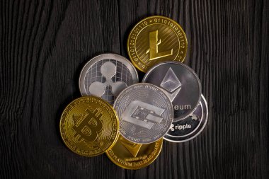 Ahşap zemin üzerinde bitcoin, dalgalanma ve ethereum sembollü gümüş ve altın sikkeler.