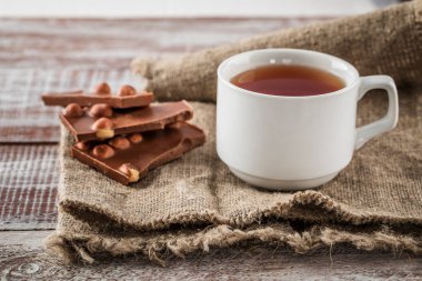 Ahşap arka plan üzerinde siyah çikolata bir fincan çay olduğunu