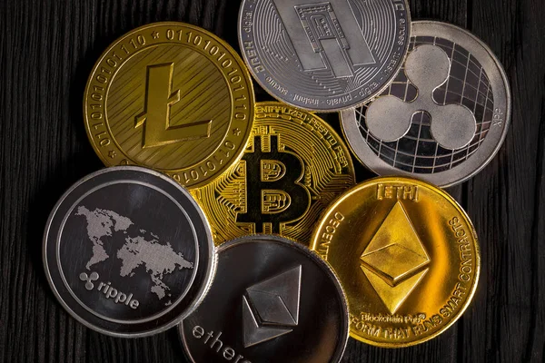 Ahşap zemin üzerinde bitcoin, dalgalanma ve ethereum sembollü gümüş ve altın sikkeler.