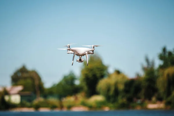 quadcopter drone flying with a camera over a lake.