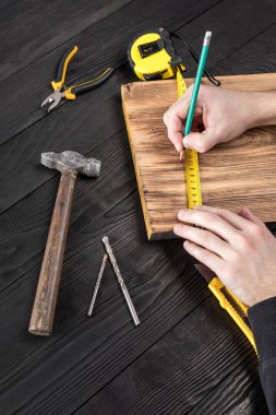 Marangoz atölyesinde ahşapla çalışır. 