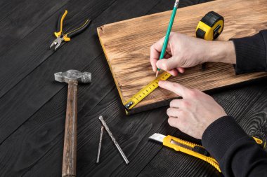 Marangoz atölyesinde ahşapla çalışır. 