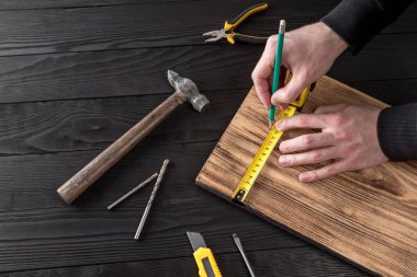 Marangoz atölyesinde ahşapla çalışır. 