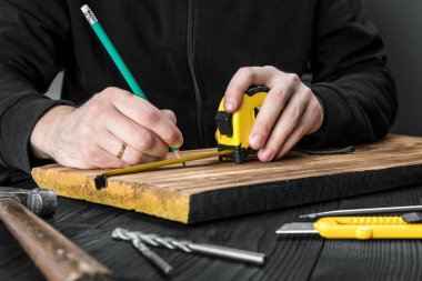 Marangoz atölyesinde ahşapla çalışır. 