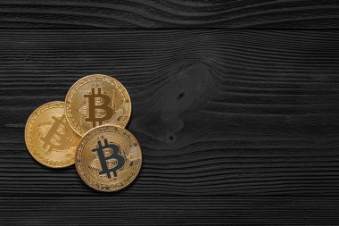 Ahşap zemin üzerinde bitcoin, dalgalanma ve ethereum sembollü gümüş ve altın sikkeler.