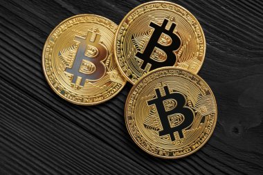 Ahşap zemin üzerinde bitcoin, dalgalanma ve ethereum sembollü gümüş ve altın sikkeler.