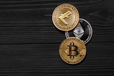 Ahşap zemin üzerinde bitcoin, dalgalanma ve ethereum sembollü gümüş ve altın sikkeler.