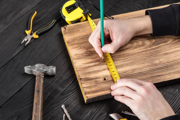 Marangoz atölyesinde ahşapla çalışır. 