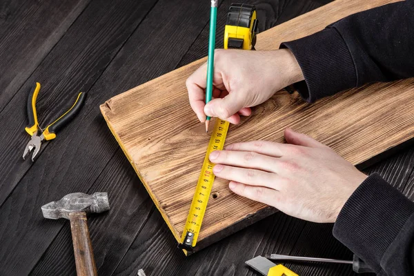 Marangoz atölyesinde ahşapla çalışır. 