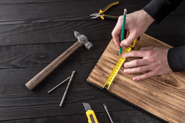 Marangoz atölyesinde ahşapla çalışır. 