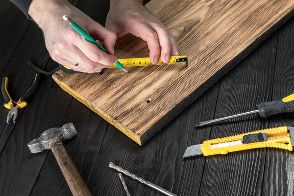 Marangoz atölyesinde ahşapla çalışır. 