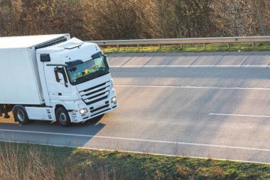 Gün batımında kırsal bir arazide beyaz bir kamyon geliyor.