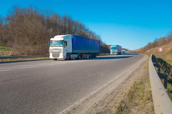 Aankomst witte vrachtwagen op de weg in een landelijk landschap bij zonsondergang — Stockfoto