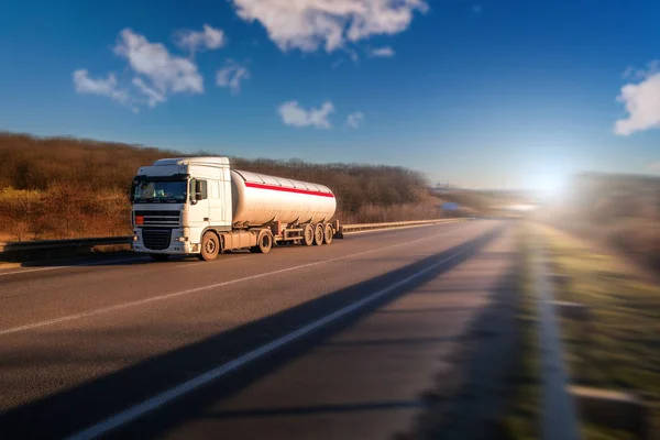 Aankomst witte vrachtwagen op de weg in een landelijk landschap bij zonsondergang — Stockfoto