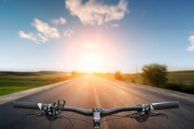 Bisikletçi asfalt yolda gidiyor.