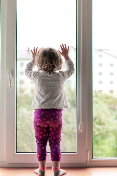 Holčička seděla na okenní římse s hračkou v dlaních — Stock fotografie