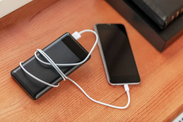 Powerbank ücretleri akıllı telefon ahşap arka plan üzerinde izole — Stok fotoğraf