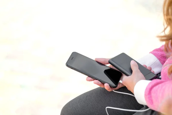 Donna mani in possesso di smartphone nero batteria di ricarica da esterno — Foto Stock