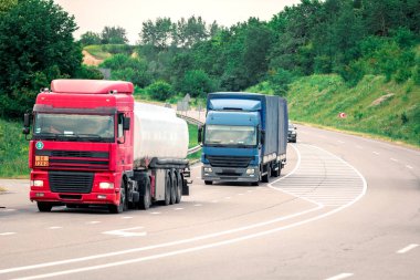Gün batımında kırsal bir arazide beyaz bir kamyon geliyor.