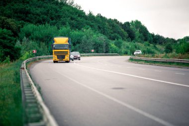 Gün batımında kırsal bir arazide beyaz bir kamyon geliyor.