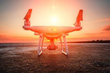 Deniz günbatımının arka planında uçan dron