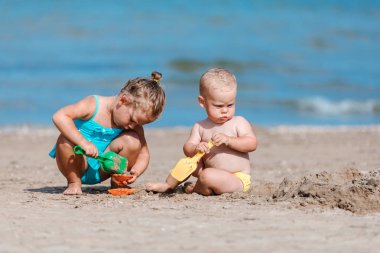 küçük erkek ve kız deniz tarafından kum ile oynarken