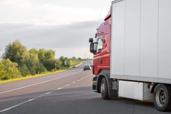 Aankomst witte vrachtwagen op de weg in een landelijk landschap bij zonsondergang — Stockfoto