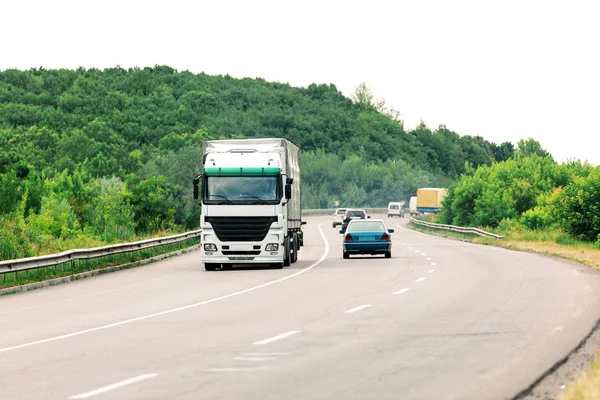 Aankomst witte vrachtwagen op de weg in een landelijk landschap bij zonsondergang — Stockfoto