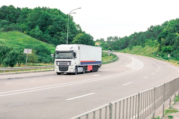 Gün batımında kırsal bir arazide beyaz bir kamyon geliyor.