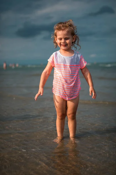 Little girl playing in the waves at sea — Stock Photo, Image