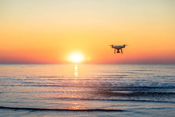 Deniz günbatımının arka planında uçan dron