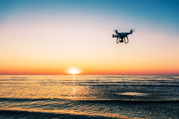 Drone voador em um fundo de pôr do sol do mar — Fotografia de Stock