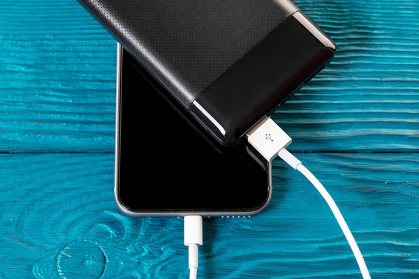 Powerbank carrega smartphone isolado em fundo de madeira — Fotografia de Stock