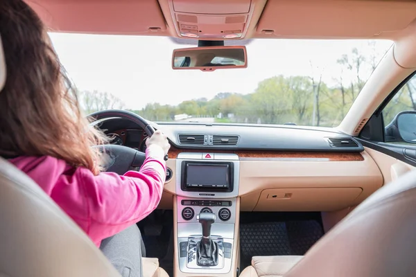 La mujer que conduce el coche moderno en el camino de asfalto hacia el —  Fotos de Stock