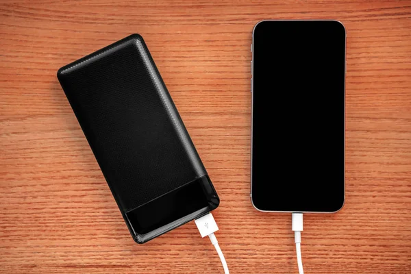 Powerbank cobra smartphone aislado sobre fondo de madera — Foto de Stock