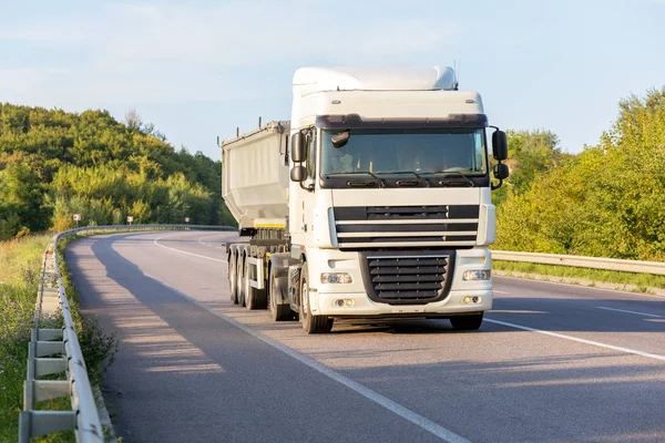 Aankomst witte vrachtwagen op de weg in een landelijk landschap bij zonsondergang — Stockfoto