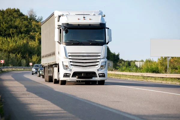 Gün batımında kırsal bir arazide beyaz bir kamyon geliyor.