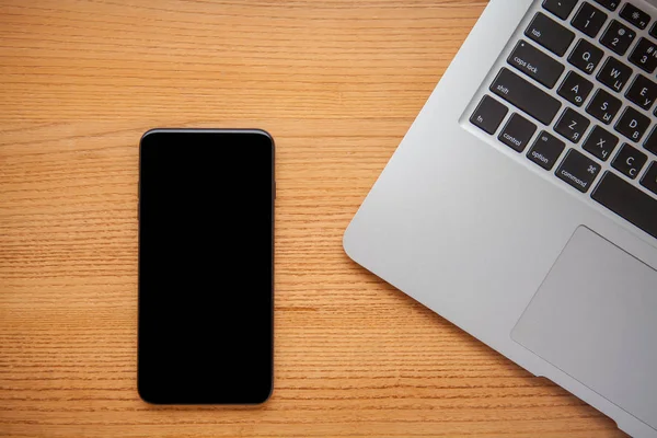 Ahşap tahta üzerinde dizüstü bilgisayar ve cep telefonu