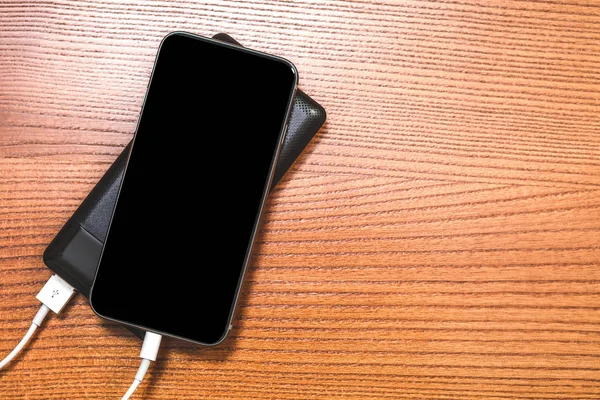 Powerbank carrega smartphone isolado em fundo de madeira — Fotografia de Stock