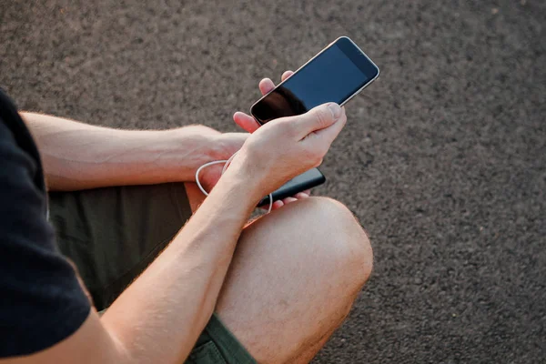 Мужские руки держат черный смартфон зарядки аккумулятор от внешней — стоковое фото