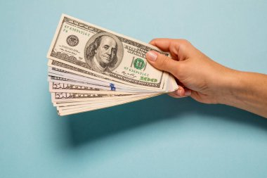 Kadın mavi arka planda dolar sayan eller